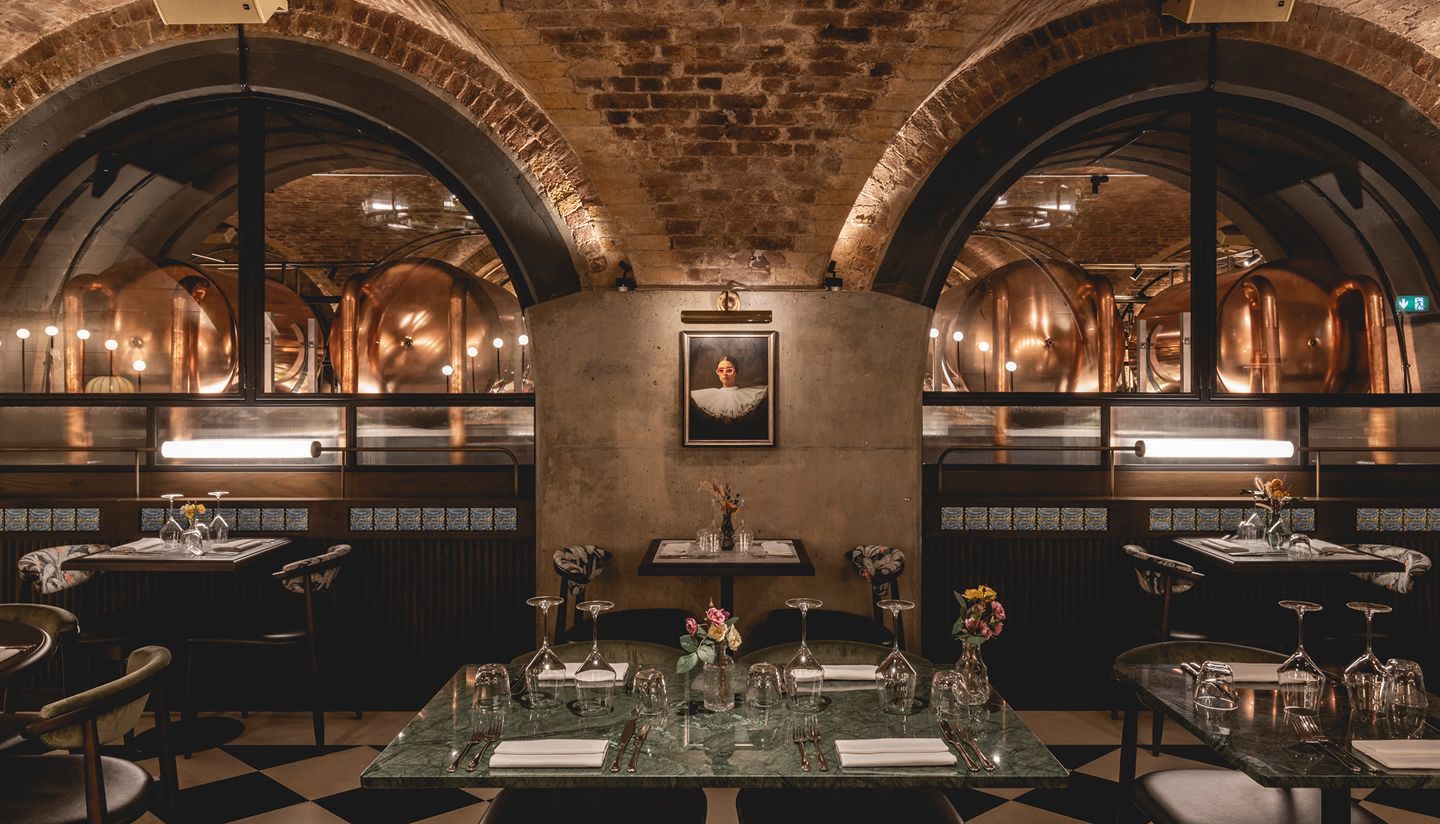 Restaurant with tables set and brick arches visible in background.