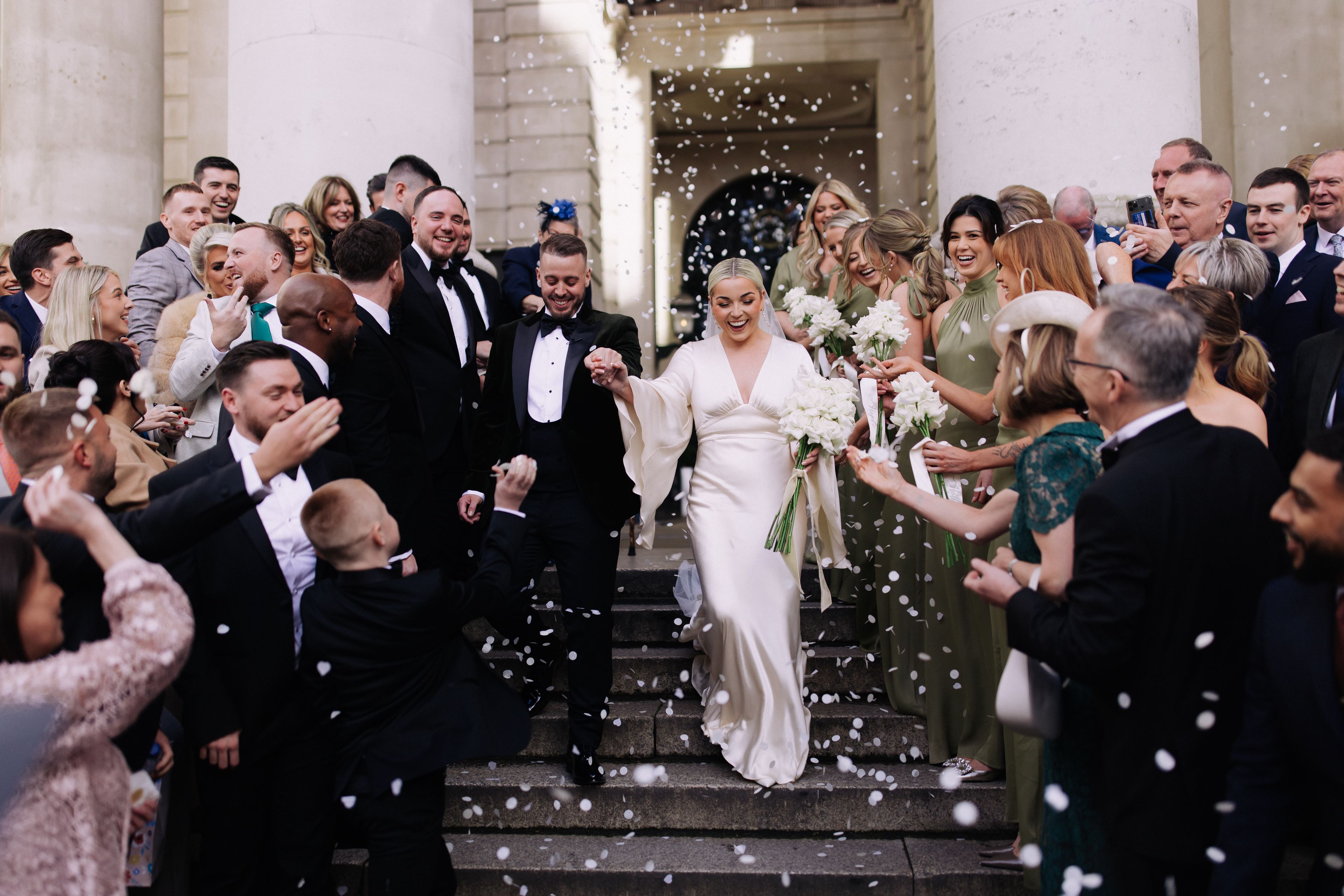 Wedding couple walking down stairs with friends and family.