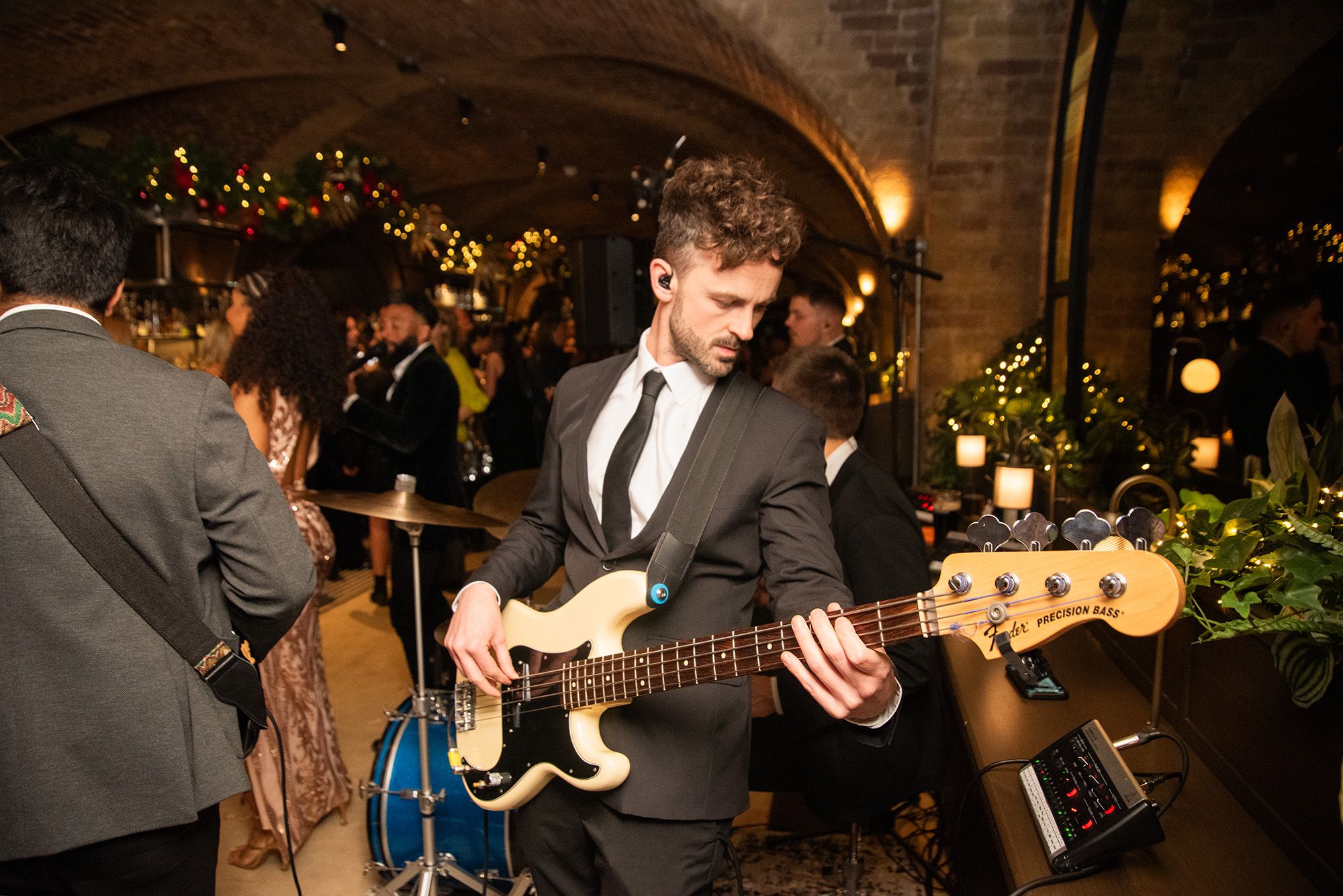 Man playing bass guitar with a band in a restaurant.
