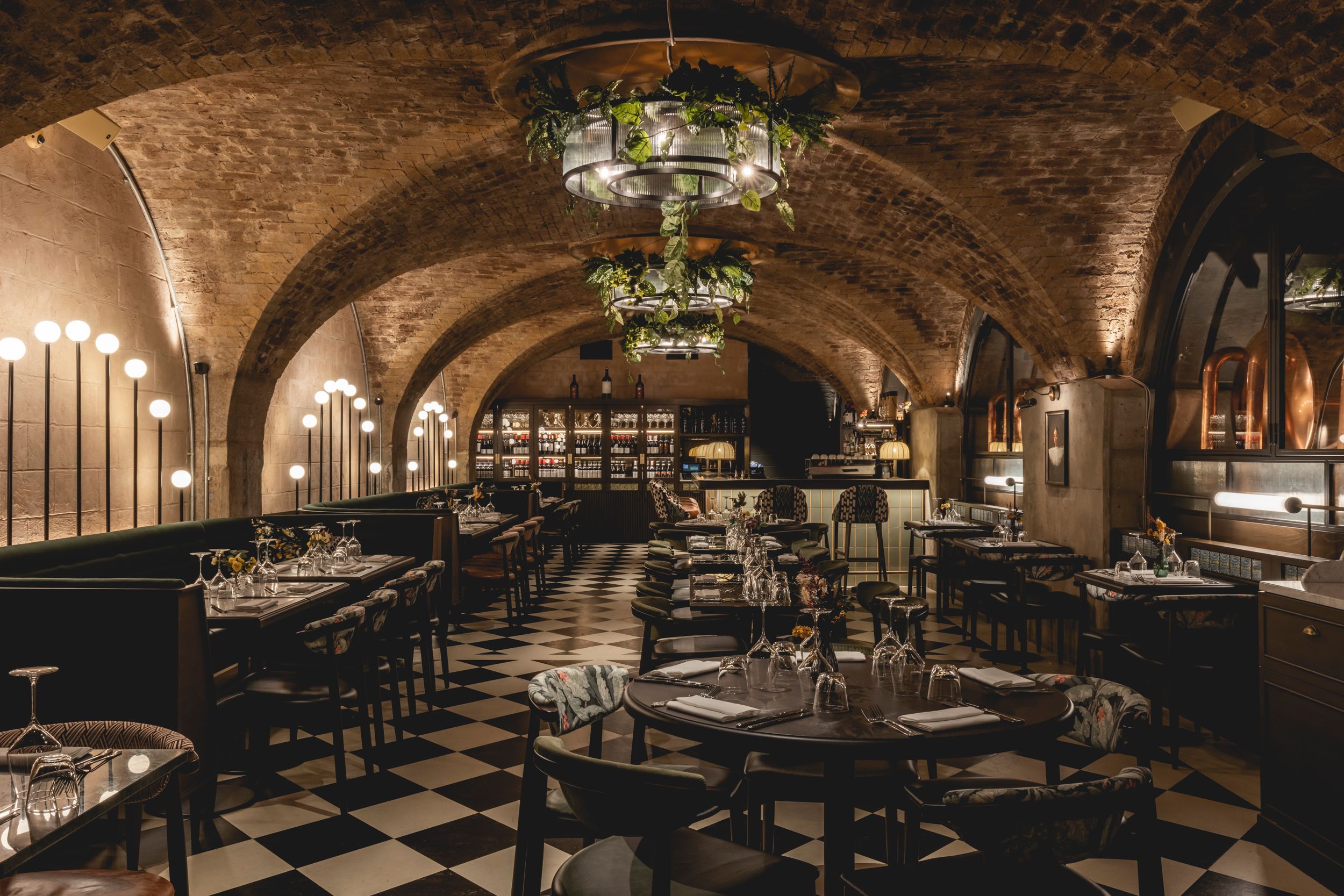Restaurant with tables laid and vaulted brickwork arches above.