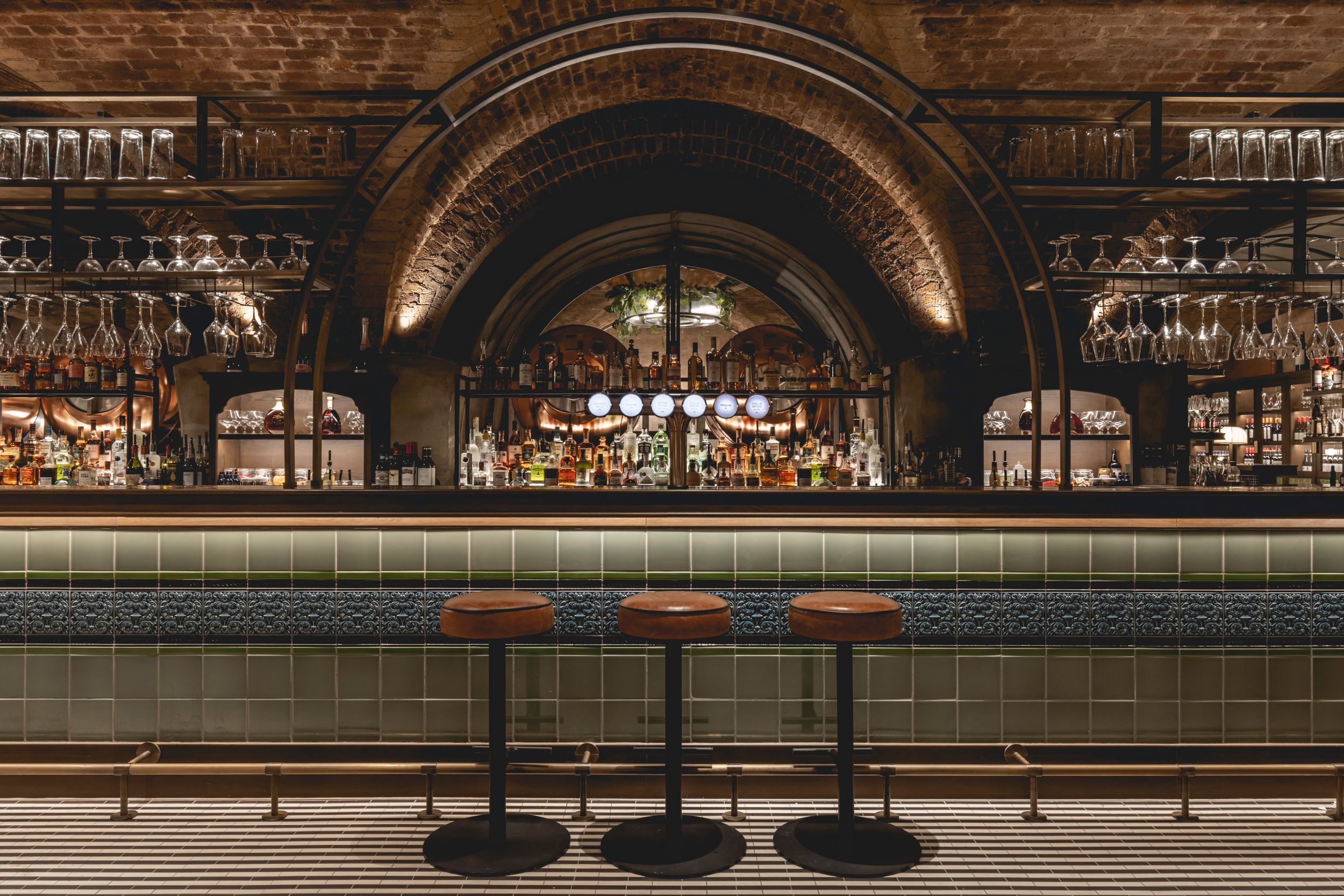 Stools at a bar with beer taps and glassware visible behind.
