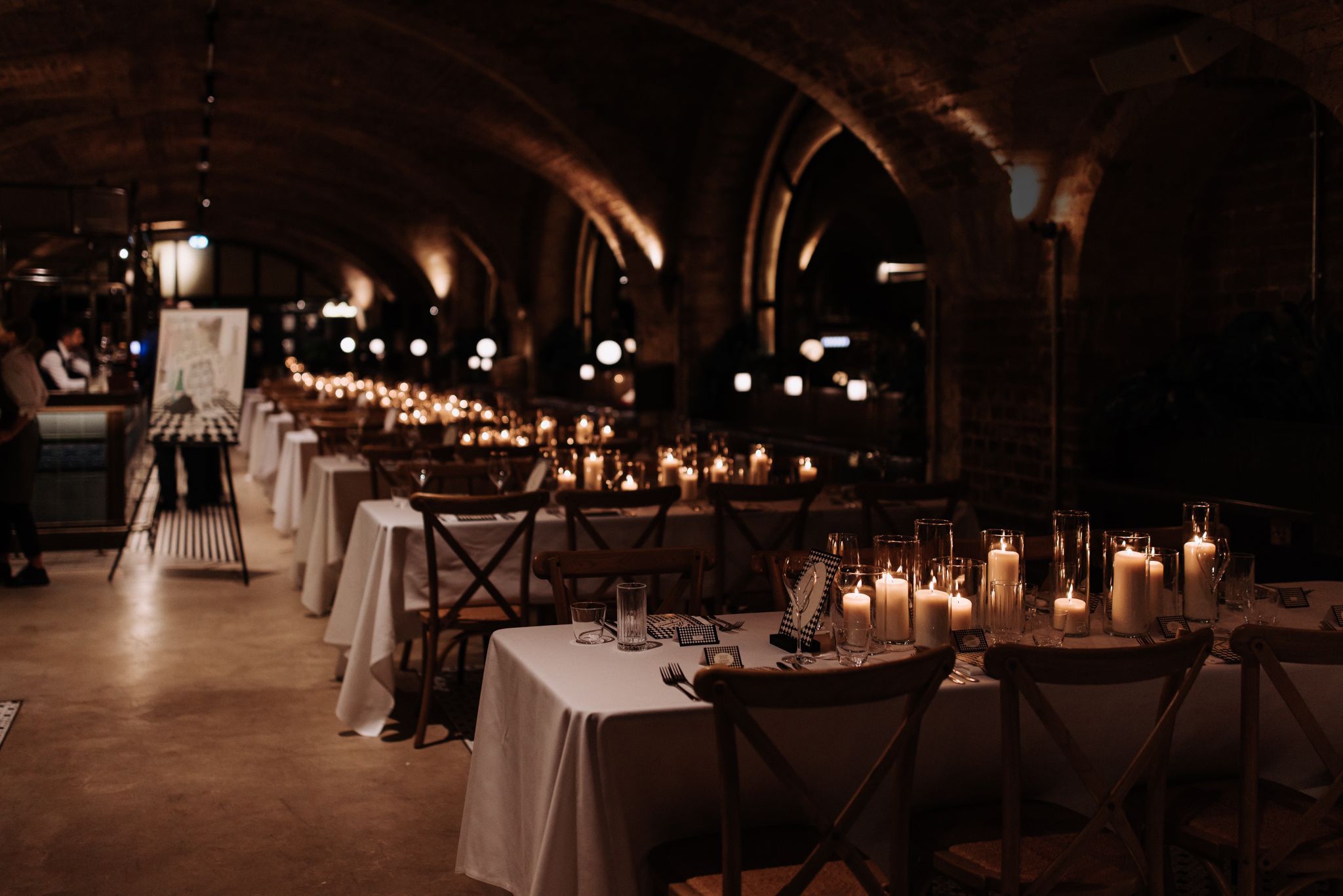 Restaurant with tables laid out for a wedding with candles and welcome sign.
