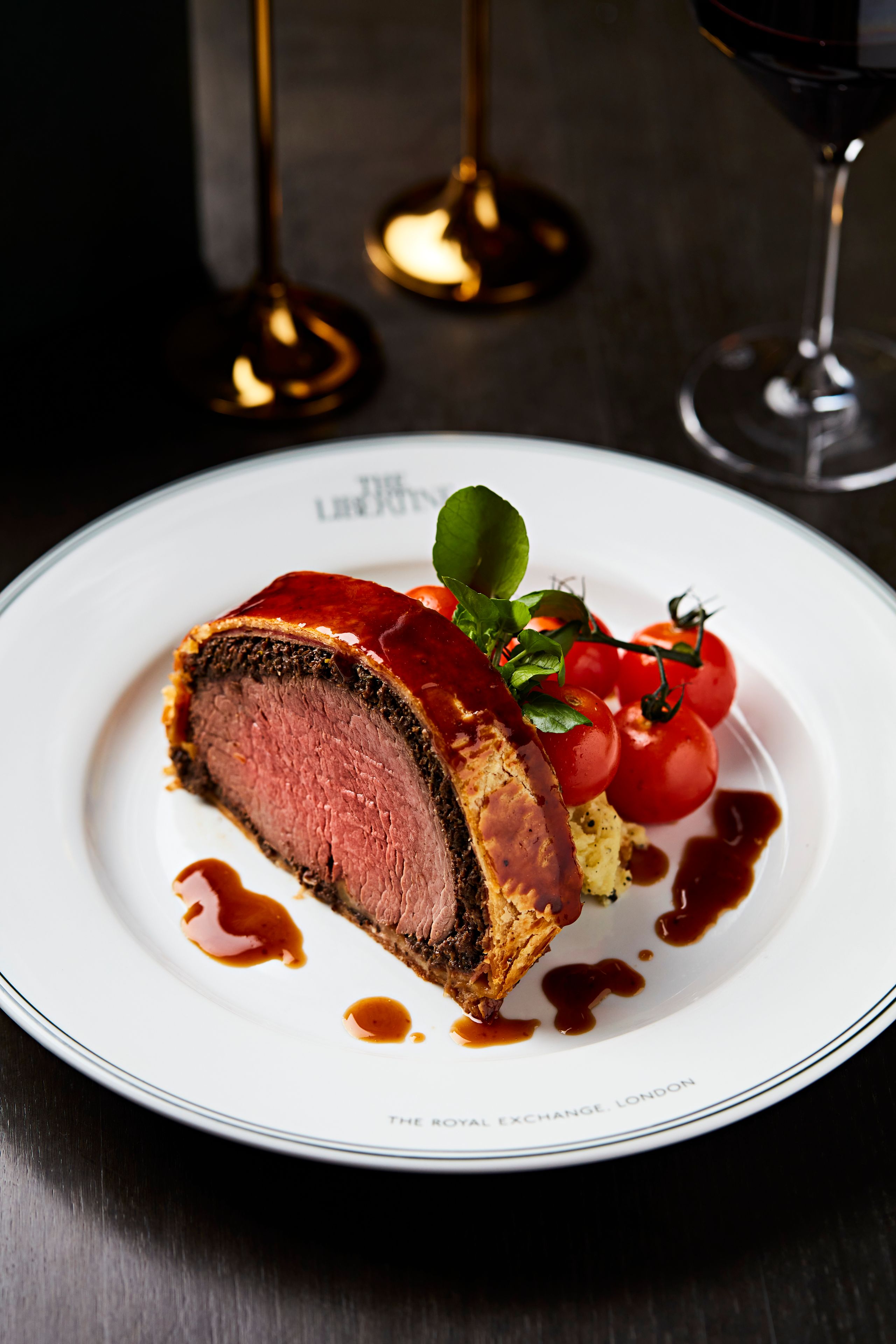 Beef wellington with tomatoes on a plate with The Libertine logo visible.