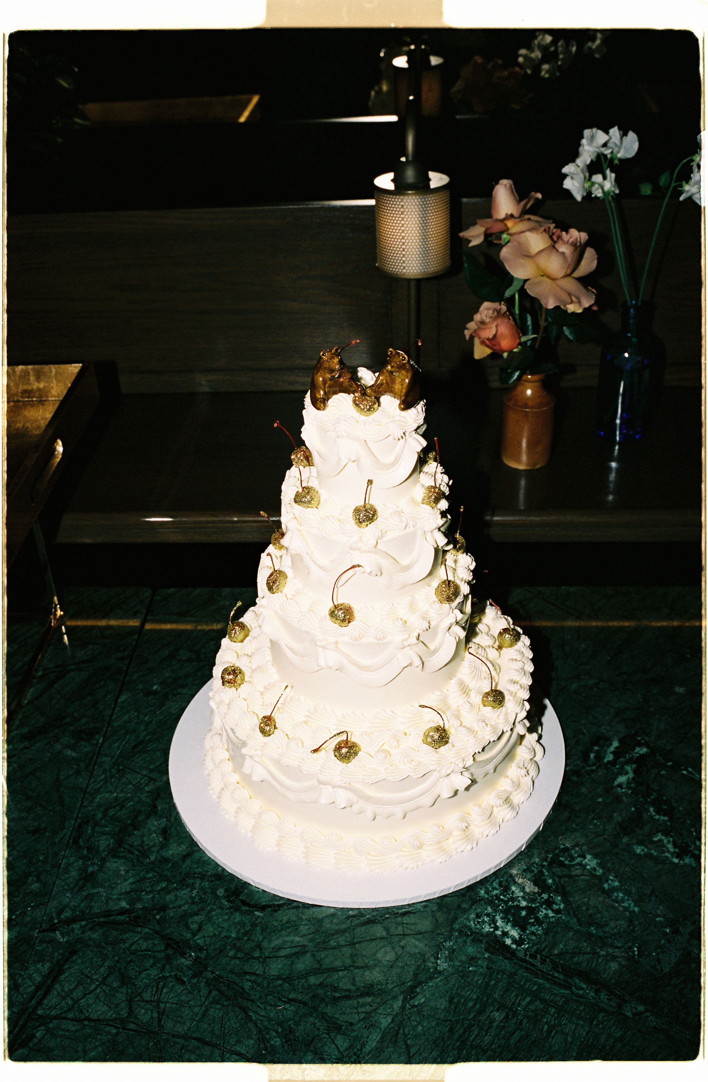 Large tiered wedding cake with golden cherries.