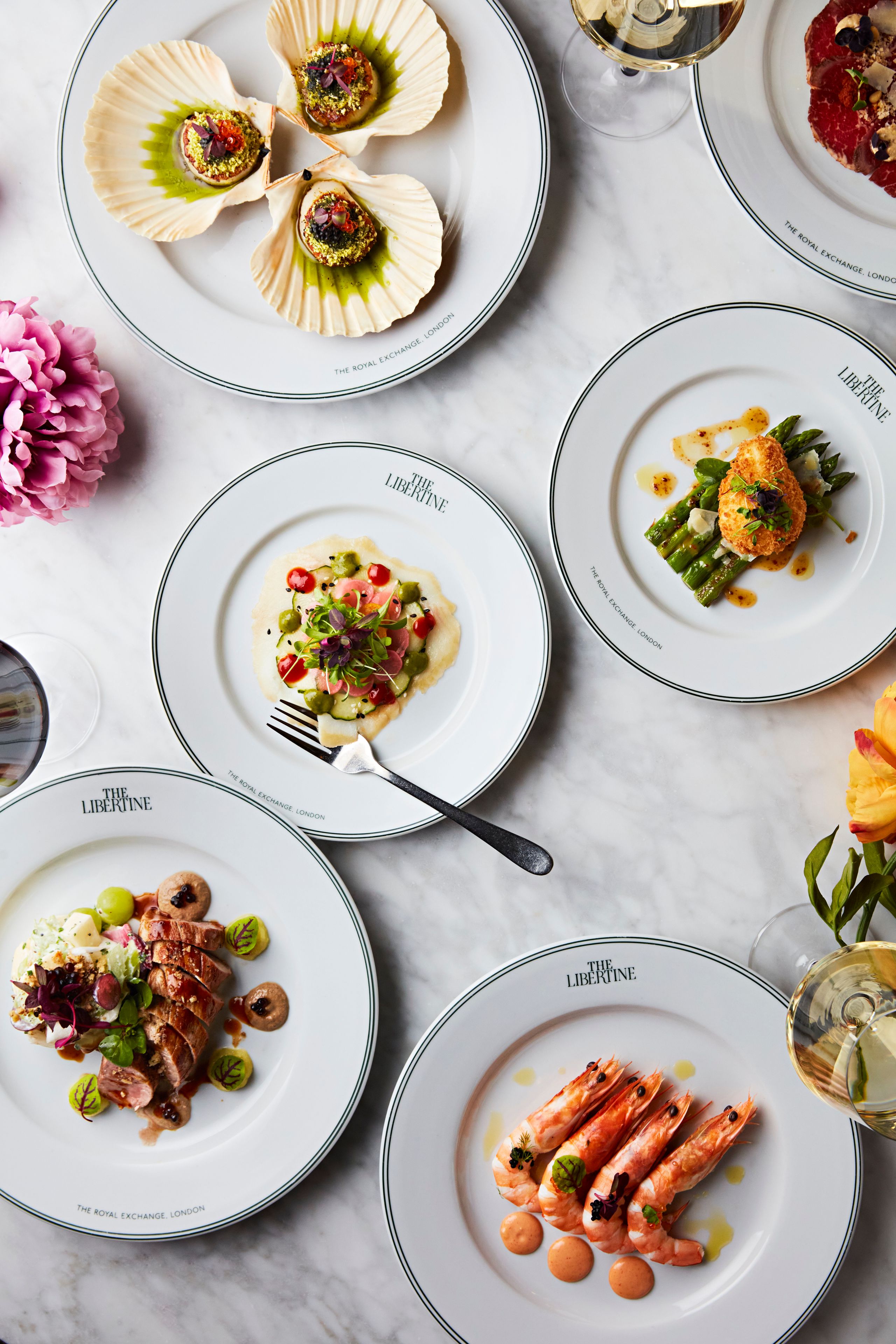 Various plates of food on a table with The Libertine logo visible.